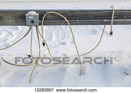Stock Photo - Detail view of extension cords buried in snow running from an outdoor power outlet, Barrow, North Slope, Arctic Alaska, USA, Winter. Fotosearch