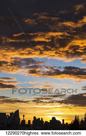 Dramatic colorful clouds at sunrise with cityscape and tree silhouette; Calgary, Alberta, Canada View Large Photo Image Stock Photograph - Dramatic colorful clouds at sunrise with cityscape and tree silhouette; Calgary, Alberta, Canada. Fotosearch