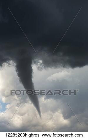 Stock Photograph - Dramatic funnel cloud created in dark storm clouds; Calgary, Alberta, Canada. Fotosearch
