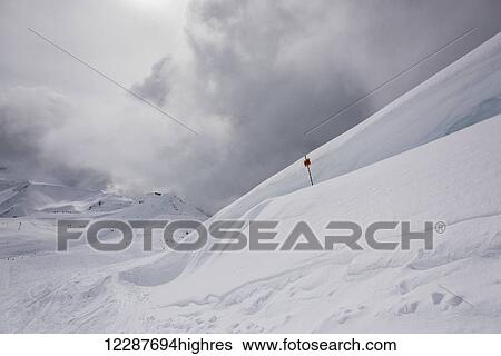 Drifting snow on a mountain top and a red flag on a ski run; Whistler, British Columbia, Canada View Large Photo Image Stock Photograph - Drifting snow on a mountain top and a red flag on a ski run; Whistler, British Columbia, Canada. Fotosearch