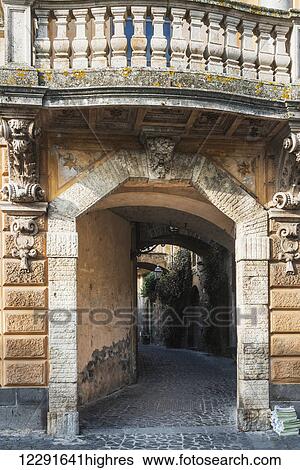 Stock Photograph - Facade of a building leading to a walkway and balusters overhead; Orvieto, Umbria, Italy. Fotosearch