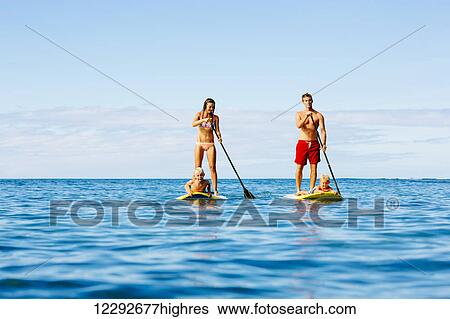 Stock Photograph - Family Having Fun Stand Up Paddling Together in the Ocean on Beautiful Sunny Morning. Fotosearch