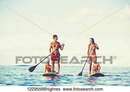 Stock Photograph - Family Having Fun Stand Up Paddling Together in the Ocean on Beautiful Sunny Morning. Fotosearch
