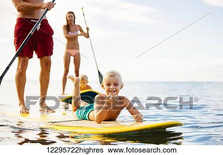 Stock Photograph - Family Having Fun Stand Up Paddling Together in the Ocean on Beautiful Sunny Morning. Fotosearch