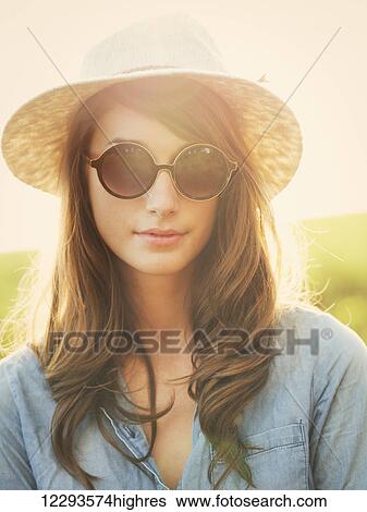Fashion portrait of beautiful young woman in hat and sunglasses oustide, bright warm sunny color tones View Large Photo Image Stock Photograph - Fashion portrait of beautiful young woman in hat and sunglasses oustide, bright warm sunny color tones. Fotosearch