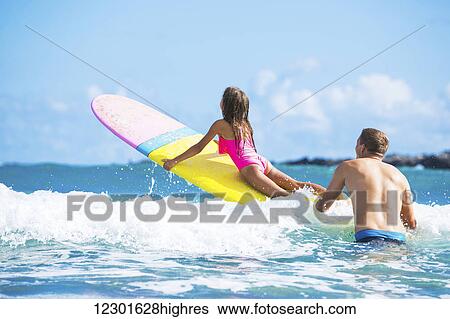 Stock Photograph - Father and Daughter Surfing Together, Summer Lifestyle Family Concept. Fotosearch