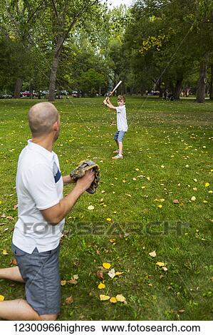 Stock Photograph - Father and son playing baseball in a park; Edmonton, Alberta, Canada. Fotosearch