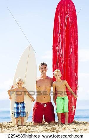Stock Photograph - Father and Two Young Sons Going Surfing at the Beach. Fotosearch
