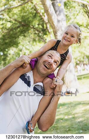 Father carrying his daughter on his shoulders in a park; Edmonton, Alberta, Canada View Large Photo Image Stock Photograph - Father carrying his daughter on his shoulders in a park; Edmonton, Alberta, Canada. Fotosearch
