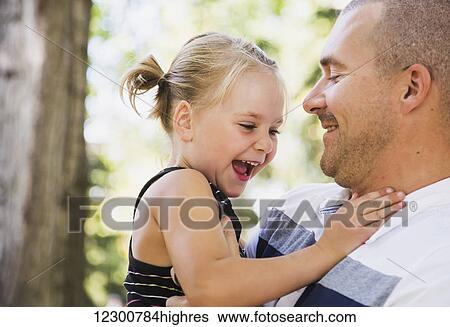 Father holding his daughter in park in autumn; Edmonton, Alberta, Canada View Large Photo Image Stock Photograph - Father holding his daughter in park in autumn; Edmonton, Alberta, Canada. Fotosearch
