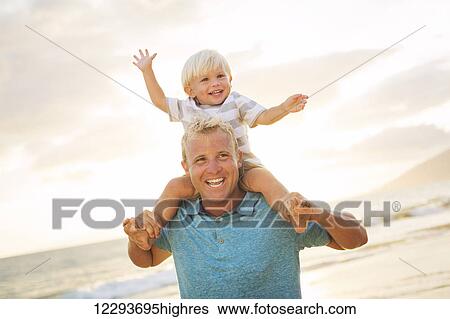 Stock Photograph - Father holding son on his shoulders on the beach at sunset.. Fotosearch