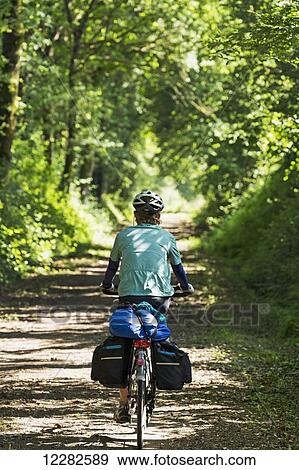 Female cyclist on gravel pathway enveloped by trees; Berrien, Brittany, France View Large Photo Image Stock Photo - Female cyclist on gravel pathway enveloped by trees; Berrien, Brittany, France. Fotosearch