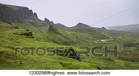 Stock Photograph - Fog over the lush green landscape with cliffs and peaks; Staffin, Scotland. Fotosearch