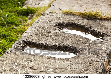 Stock Photograph - Footprints in a stone wall filled with water; Delphi, Greece. Fotosearch