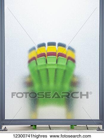 Stock Photograph - Four colourful deck chairs stacked and leaning against frosted glass; Toronto, Ontario, Canada. Fotosearch