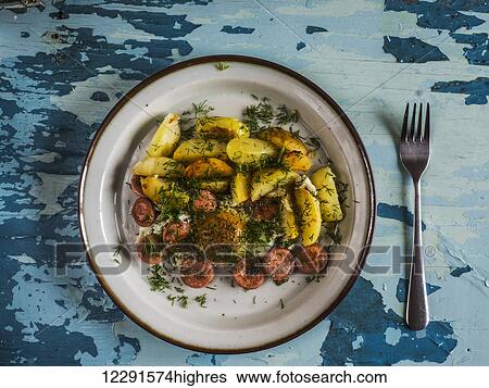 Stock Photograph - Fried eggs with fried potatoes and sausages on plate on old weathered painted table; Kiev, Ukraine. Fotosearch