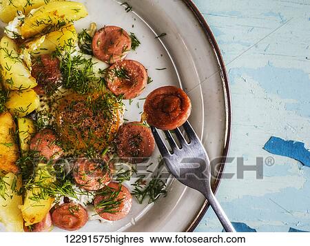 Fried eggs with fried potatoes and sausages on plate on old weathered painted table; Kiev, Ukraine View Large Photo Image Stock Photograph - Fried eggs with fried potatoes and sausages on plate on old weathered painted table; Kiev, Ukraine. Fotosearch