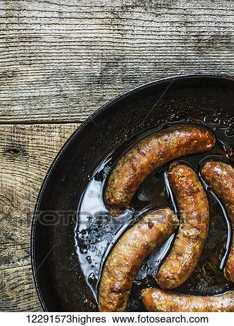 Fried homemade sausages in pan on old weathered wooden table; Kiev, Ukraine View Large Photo Image Stock Photograph - Fried homemade sausages in pan on old weathered wooden table; Kiev, Ukraine. Fotosearch