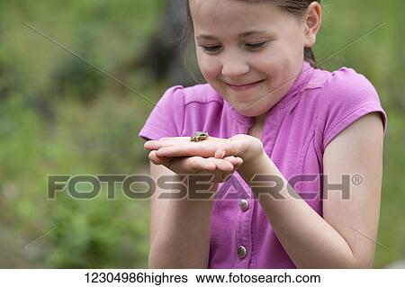 Stock Photograph - Girl holding a wood frog, Palmer, Southcentral Alaska, summer.. Fotosearch