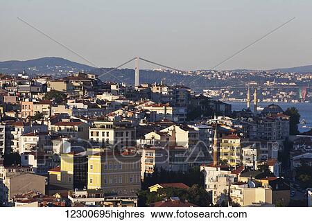 Stock Photograph - Golden hour light view over Istanbul rooftops towards Bosphurus Bridge between Europe and Asia; Istanbul, Turkey. Fotosearch