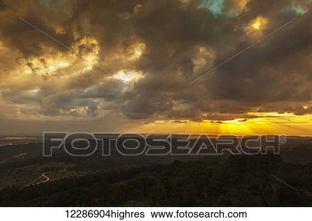 Stock Photograph - Golden sunset with glowing clouds and silhouetted landscape; Israel. Fotosearch