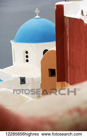 Stock Photograph - Greek orthodox church with blue dome in the village of Oia; Oia, Santorini, Greece. Fotosearch