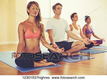 Stock Photograph - Group of People Relaxing and Meditating in Yoga Class. Wellness and Healthy Lifestyle.. Fotosearch
