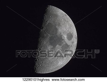 Stock Photograph - Half of the moon illuminated in a dark sky. Fotosearch