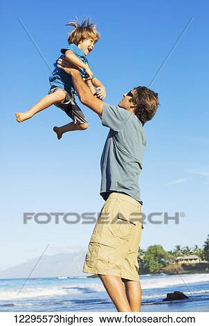 Stock Photograph - Happy father and son playing on tropical beach, carefree happy fun smiling lifestyle. Fotosearch