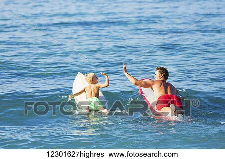 Happy Father and Young Son Going Surfing Together. Giving each other a Hi-Five! View Large Photo Image Stock Photograph - Happy Father and Young Son Going Surfing Together. Giving each other a Hi-Five!. Fotosearch