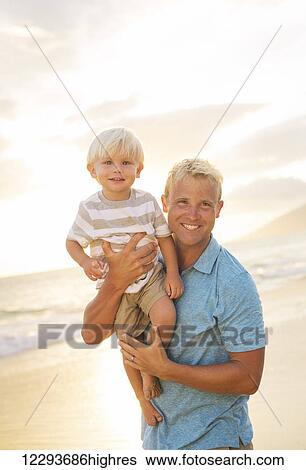 Stock Photograph - Happy loving father and son on the beach at sunset. Fotosearch