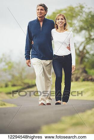 Happy loving middle aged couple walking on beautiful country road View Large Photo Image Stock Photograph - Happy loving middle aged couple walking on beautiful country road. Fotosearch