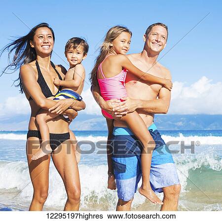 Stock Photograph - Happy Mixed Race Family of Four on Tropical Sunny Beach. Fotosearch