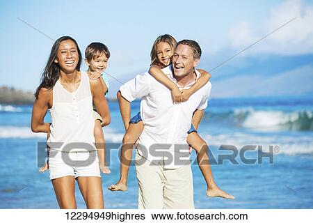 Stock Photograph - Happy Mixed Race Family of Four on the Beach. Fotosearch