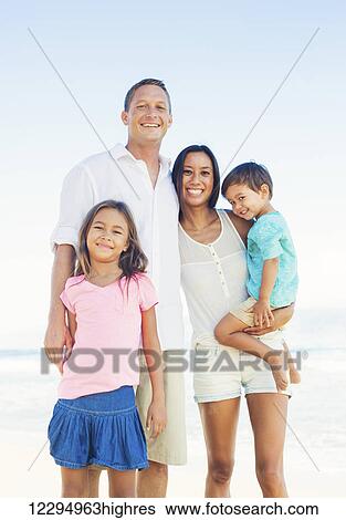 Stock Photograph - Happy Portrait of Mixed Race Family on the Beach. Fotosearch
