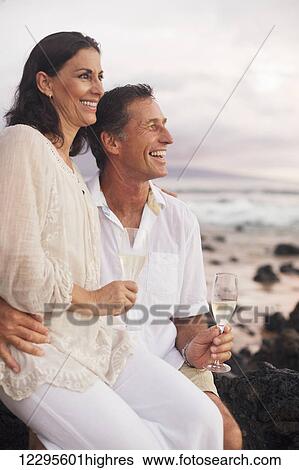 Happy Romantic Mature Couple Drinking Champagne on the Beach at Sunset. View Large Photo Image Stock Photograph - Happy Romantic Mature Couple Drinking Champagne on the Beach at Sunset.. Fotosearch