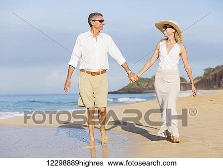 Happy Romantic Middle Aged Couple Enjoying Walk on the Beach, Vacation Retirement Concept View Large Photo Image Stock Photograph - Happy Romantic Middle Aged Couple Enjoying Walk on the Beach, Vacation Retirement Concept. Fotosearch