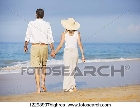 Stock Photograph - Happy senior couple on the beach. Retirement Luxury Tropical Resort. Fotosearch