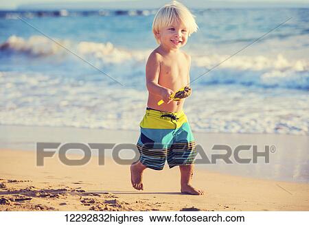 Stock Photograph - Happy young boy playing at the beach. Fotosearch