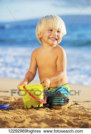 Happy young boy playing at the beach View Large Photo Image Stock Photograph - Happy young boy playing at the beach. Fotosearch