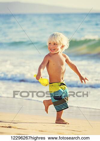 Stock Photograph - Happy young boy playing at the beach. Fotosearch