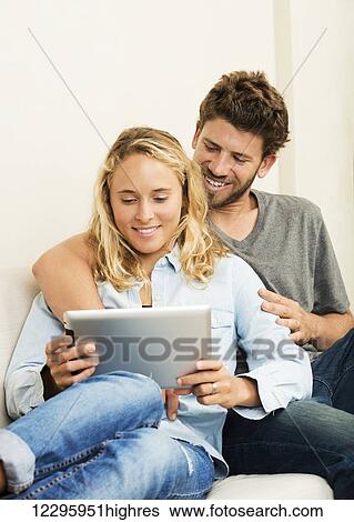 Stock Photograph - Happy young couple at home using digital tablet. Fotosearch