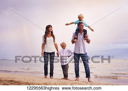 Stock Photograph - Happy young family on the beach at sunset. Fotosearch