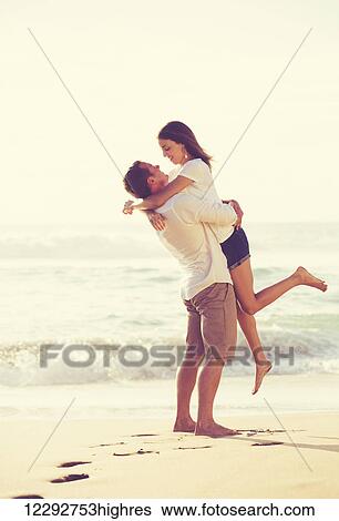 Stock Photograph - Happy Young Romantic Couple Playing and Having Fun on the Beach. Fotosearch