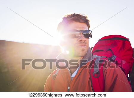 Hiker with backpack standing on mountain top enjoying the view View Large Photo Image Stock Photograph - Hiker with backpack standing on mountain top enjoying the view. Fotosearch