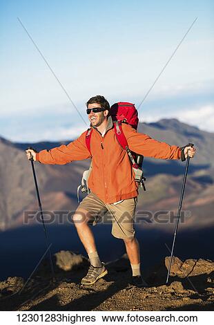 Stock Photograph - Hiker with backpack standing on mountain top enjoying the view. Fotosearch