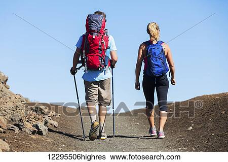 Stock Photograph - Hiking in the mountains. Athletic couple with backpacks enjoying hike outdoors.. Fotosearch