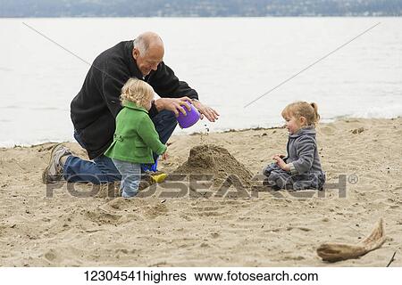 In cold weather, a grandfather plays with his two grand-daughters on the beach at Stanley Park; Vancouver, British Columbia, Canada View Large Photo Image Stock Photograph - In cold weather, a grandfather plays with his two grand-daughters on the beach at Stanley Park; Vancouver, British Columbia, Canada. Fotosearch
