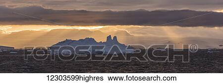 Stock Photograph - Jagged iceberg in silhouette against dawn sky; Antarctica. Fotosearch