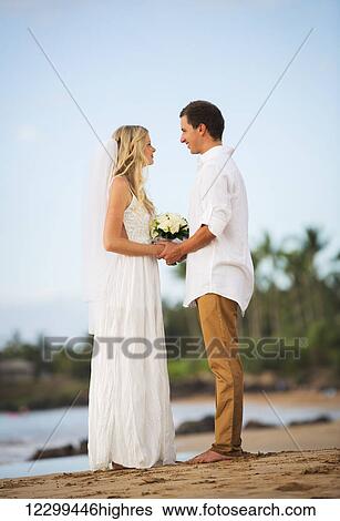 Just married couple holding hands on the beach at sunset, Intimate loving moment at wedding View Large Photo Image Stock Photograph - Just married couple holding hands on the beach at sunset, Intimate loving moment at wedding. Fotosearch